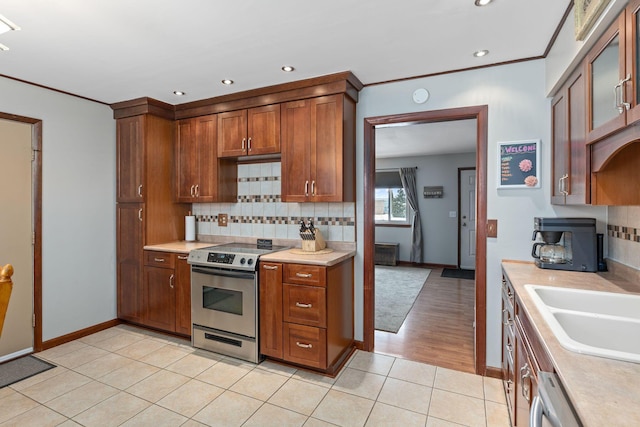 kitchen with sink, stainless steel appliances, backsplash, crown molding, and light tile patterned floors