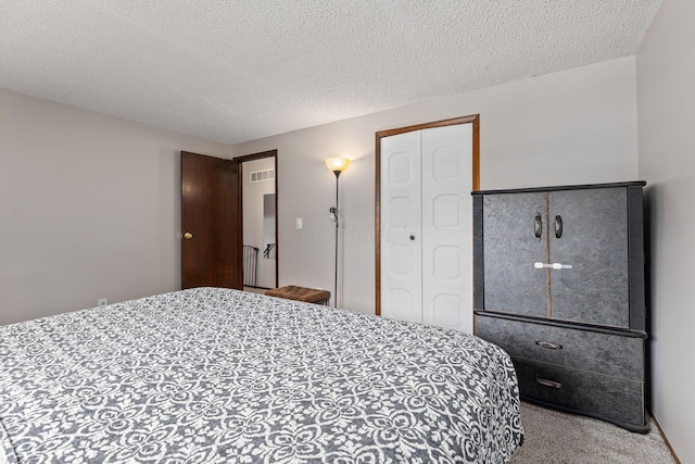 bedroom with a textured ceiling, light colored carpet, and a closet