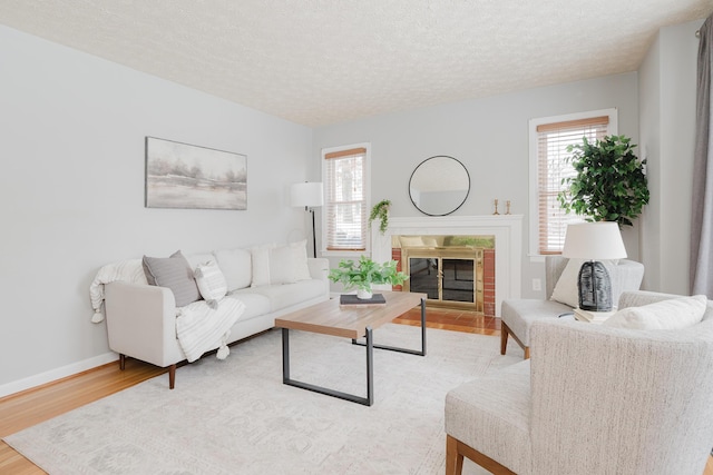 living room featuring a fireplace, a textured ceiling, and light hardwood / wood-style flooring