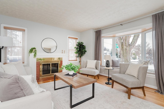 living room featuring wood-type flooring, a brick fireplace, and a wealth of natural light