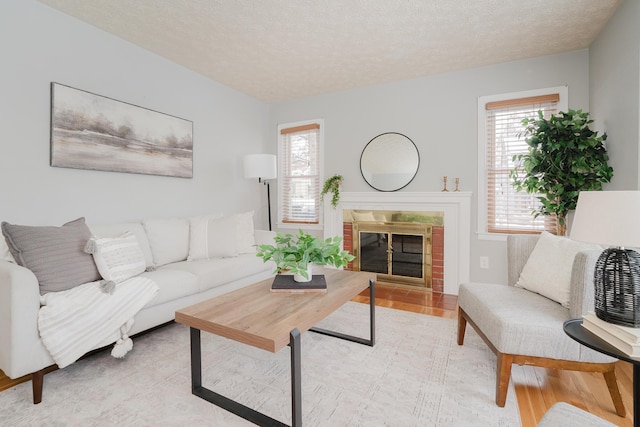 living room with a fireplace, a textured ceiling, and light hardwood / wood-style flooring