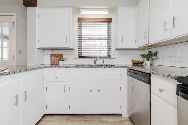 kitchen featuring light stone countertops, white cabinetry, stainless steel dishwasher, and sink