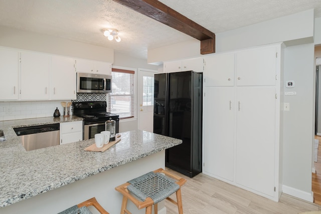 kitchen featuring light stone counters, white cabinetry, backsplash, and appliances with stainless steel finishes