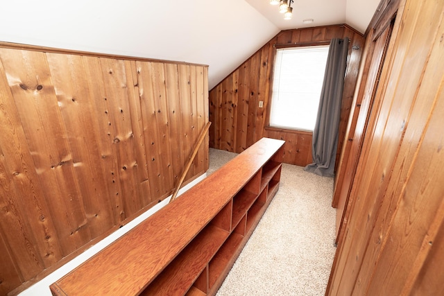 hall featuring light carpet, wood walls, and lofted ceiling