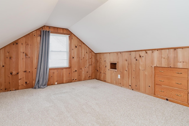 bonus room featuring light carpet, wooden walls, and lofted ceiling