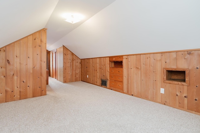 bonus room featuring wood walls, light carpet, and vaulted ceiling