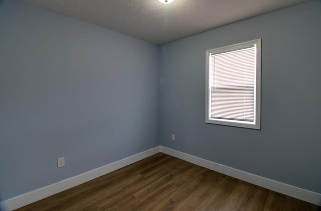 unfurnished room featuring a textured ceiling and dark hardwood / wood-style floors