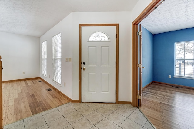 entryway featuring light tile patterned floors, a healthy amount of sunlight, and a textured ceiling