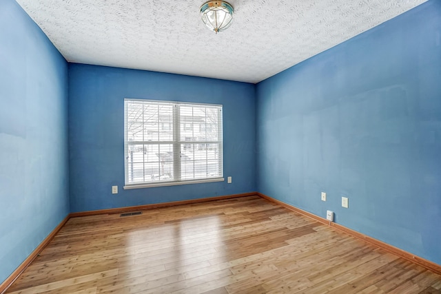 spare room with a textured ceiling and light wood-type flooring