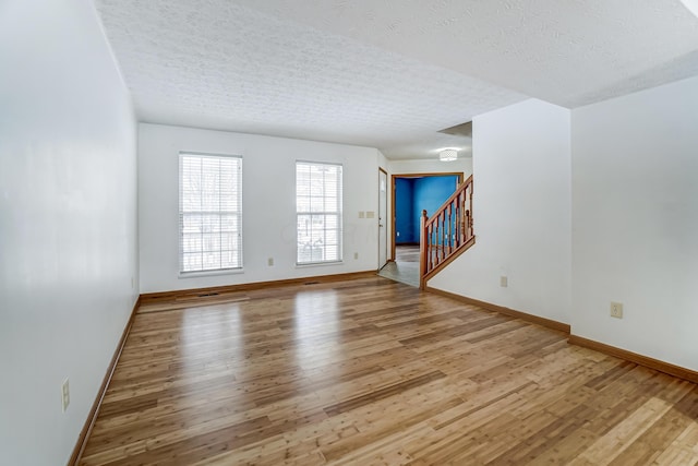 unfurnished room with a textured ceiling and light hardwood / wood-style flooring