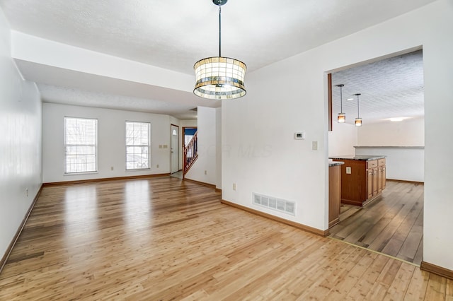 empty room with a chandelier and light hardwood / wood-style floors