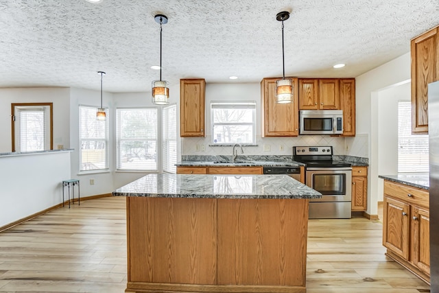 kitchen with a center island, decorative light fixtures, and appliances with stainless steel finishes