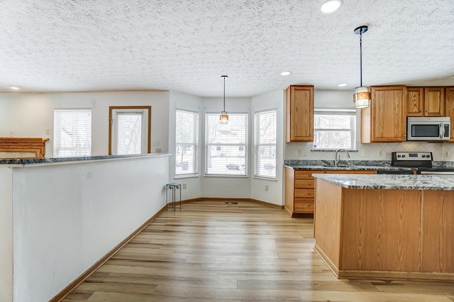 kitchen featuring appliances with stainless steel finishes, a textured ceiling, pendant lighting, and a healthy amount of sunlight