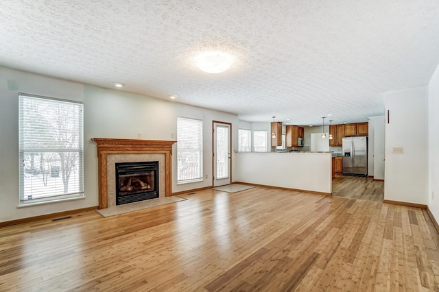 unfurnished living room with a fireplace, a textured ceiling, and light wood-type flooring