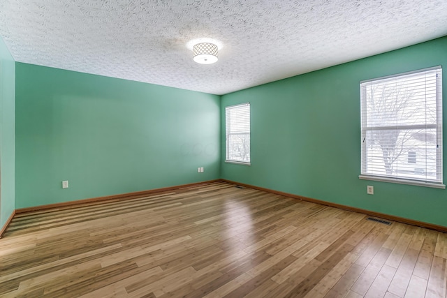 spare room featuring wood-type flooring and a textured ceiling