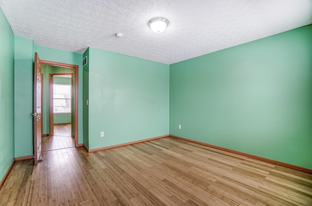 spare room with light hardwood / wood-style floors and a textured ceiling