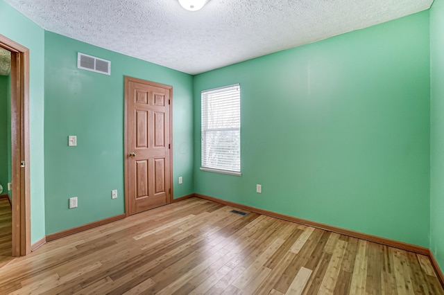 unfurnished bedroom with a textured ceiling and light hardwood / wood-style flooring