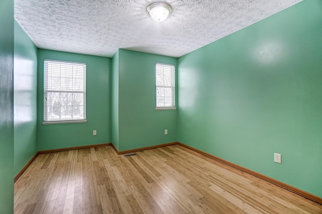 unfurnished room with a textured ceiling, light wood-type flooring, and plenty of natural light