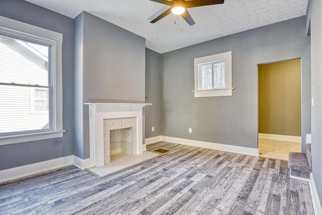 unfurnished living room featuring a textured ceiling, a tile fireplace, and hardwood / wood-style flooring