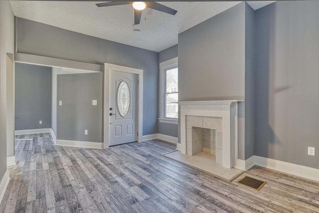 entrance foyer with light wood-type flooring, a fireplace, a textured ceiling, and ceiling fan