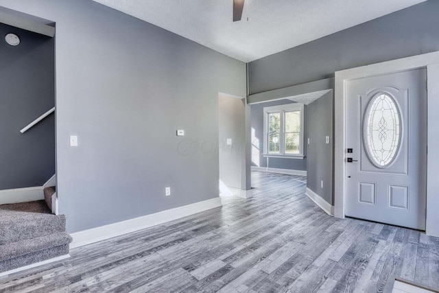 foyer featuring wood-type flooring, a textured ceiling, and ceiling fan