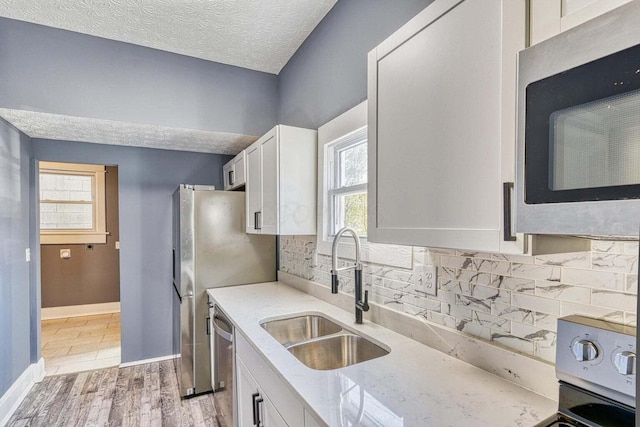 kitchen with sink, white cabinets, tasteful backsplash, and appliances with stainless steel finishes