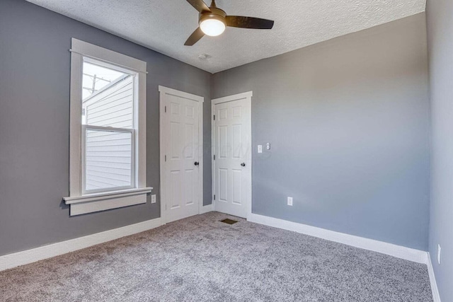 spare room with a textured ceiling, ceiling fan, a healthy amount of sunlight, and carpet floors