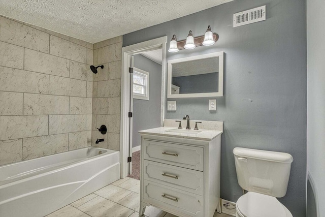 full bathroom with tile patterned flooring, toilet, vanity, tiled shower / bath, and a textured ceiling