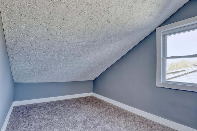 bonus room featuring a textured ceiling, vaulted ceiling, carpet flooring, and plenty of natural light