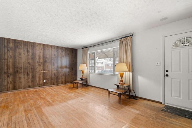 entryway with a textured ceiling, wooden walls, and wood-type flooring