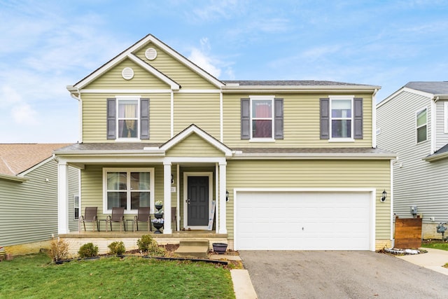 view of front of home with a garage, a front lawn, and covered porch