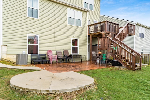 rear view of property featuring cooling unit, a wooden deck, a lawn, and a patio