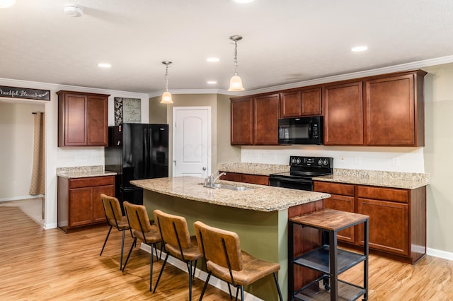 kitchen featuring pendant lighting, sink, a kitchen bar, black appliances, and a center island with sink