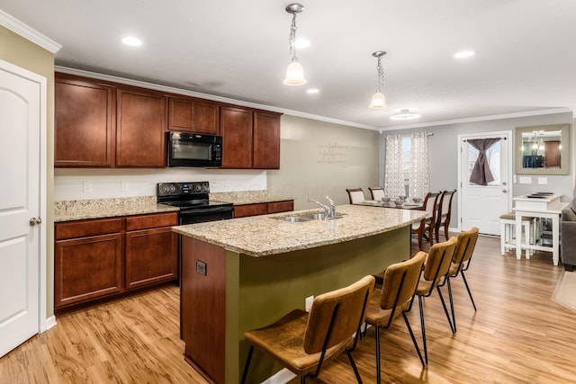 kitchen with pendant lighting, sink, black appliances, crown molding, and a center island with sink