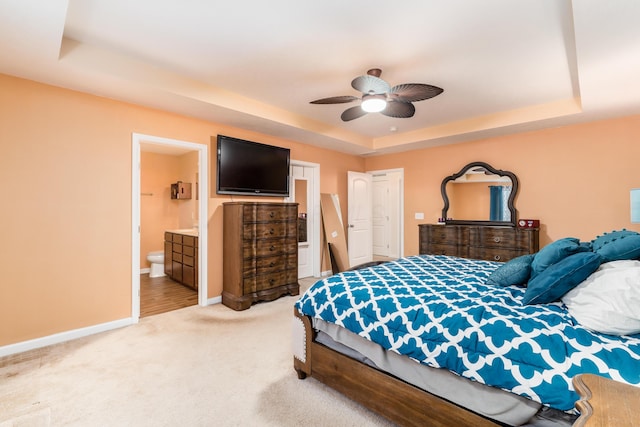 bedroom with a raised ceiling, carpet floors, connected bathroom, and ceiling fan