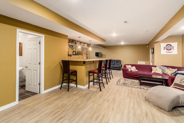 living room with bar area and hardwood / wood-style floors