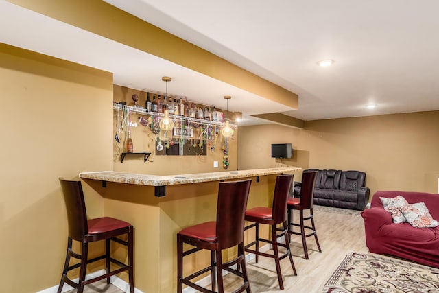 bar with decorative light fixtures and light hardwood / wood-style flooring