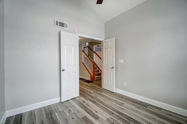 unfurnished room with ceiling fan, light wood-type flooring, and high vaulted ceiling