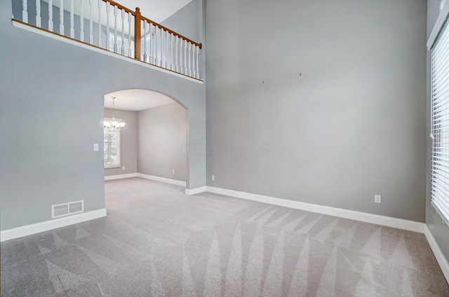 carpeted spare room featuring a high ceiling and a notable chandelier