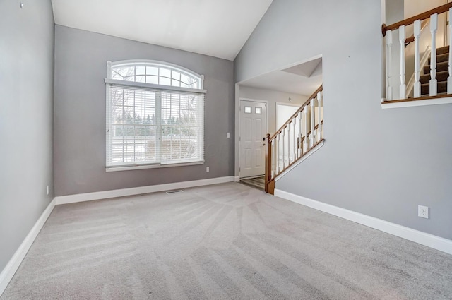 carpeted entryway featuring high vaulted ceiling