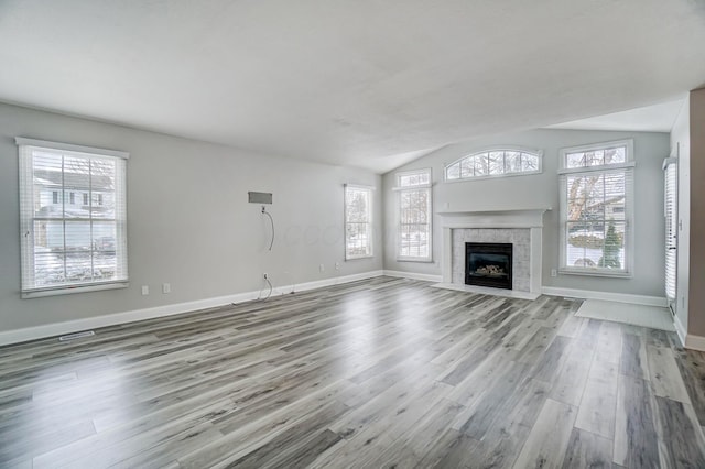 unfurnished living room with a fireplace, lofted ceiling, and light hardwood / wood-style flooring