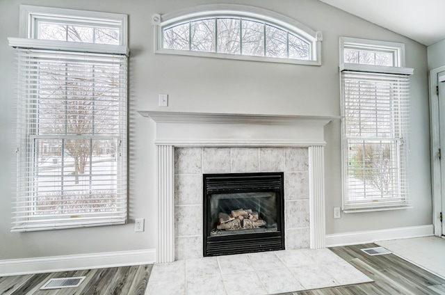 details with wood-type flooring and a tiled fireplace