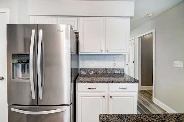 kitchen with stainless steel fridge with ice dispenser, backsplash, dark stone countertops, hardwood / wood-style floors, and white cabinets