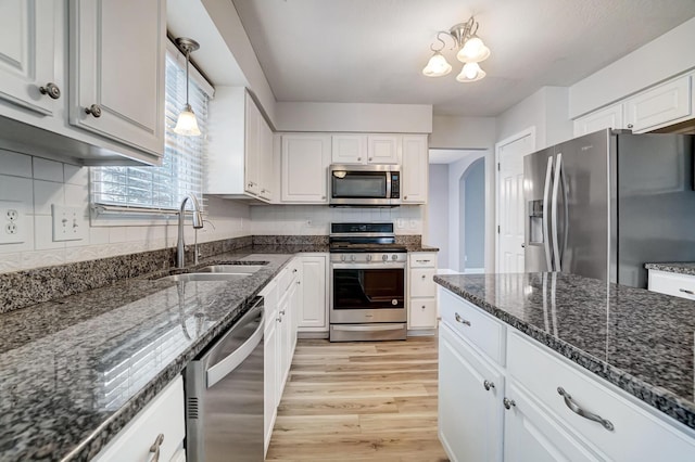 kitchen with sink, stainless steel appliances, dark stone counters, light hardwood / wood-style floors, and white cabinets