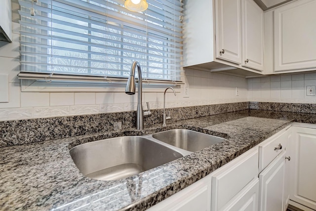 kitchen with dark stone countertops, sink, and white cabinets