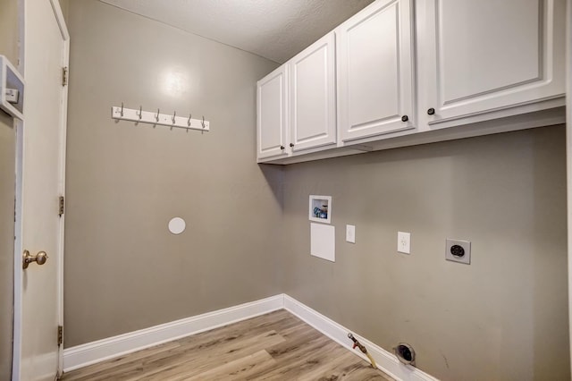 laundry room featuring cabinets, hookup for an electric dryer, light hardwood / wood-style flooring, hookup for a washing machine, and a textured ceiling