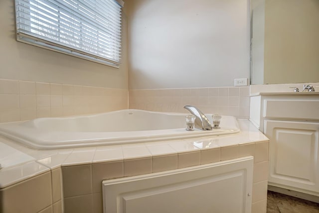 bathroom featuring tiled tub and vanity