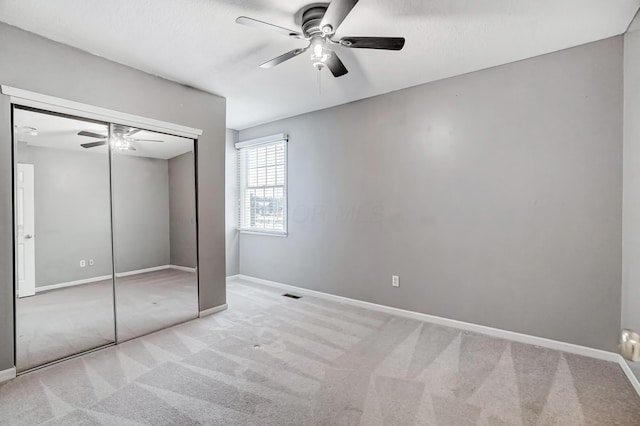 unfurnished bedroom with light colored carpet, a closet, and ceiling fan