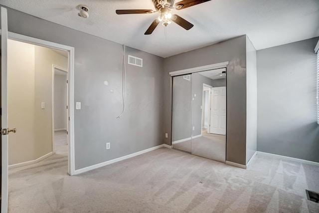 unfurnished bedroom with ceiling fan, light carpet, and a closet