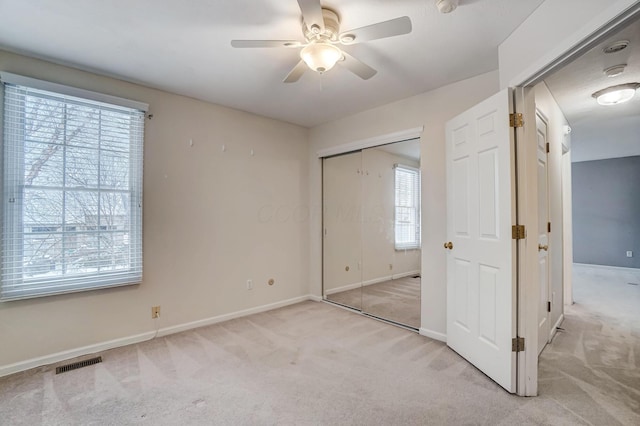 unfurnished bedroom with ceiling fan, a closet, and light carpet